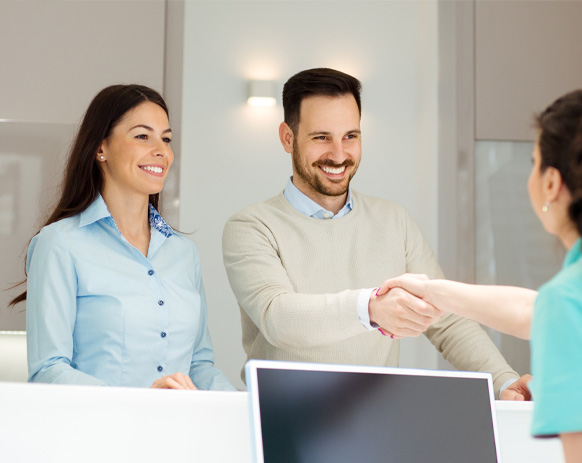 Two dental patients checking in at dental office reception desk