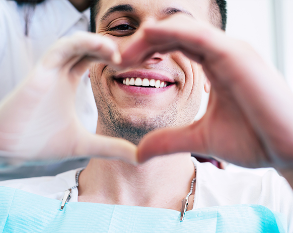 Man making heart shape with his hands over his smile