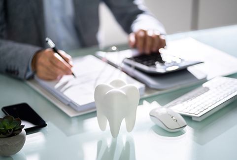 Person doing paperwork with a tooth mold on their desk