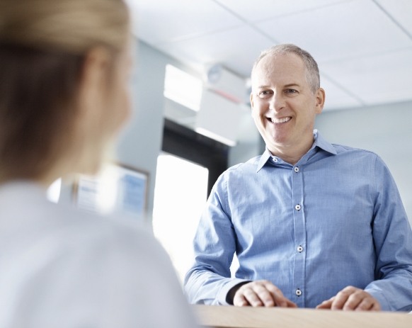 Man talking to dental team member about preventive dental emergencies