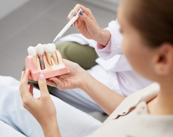 Dentist using model to describe the four step dental implant process