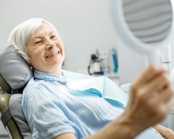 Woman looking at smile after dental implants