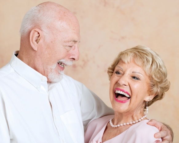 Older couple with dental implants smiling together