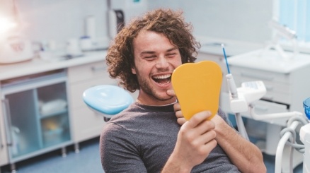 Man looking at healthy smile during preventive dentistry visit