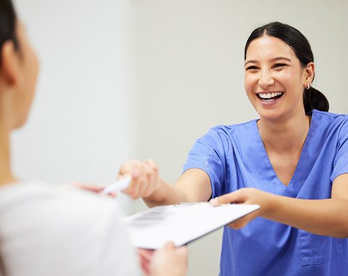 Dental assistant smiling while handing patient form