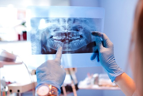 Dentist pointing to patient's dental X-ray in office