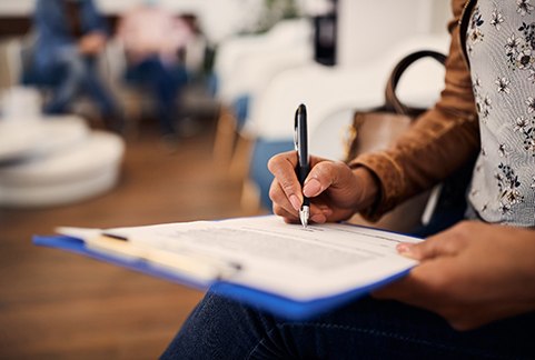 Woman filling out dental insurance form in lobby