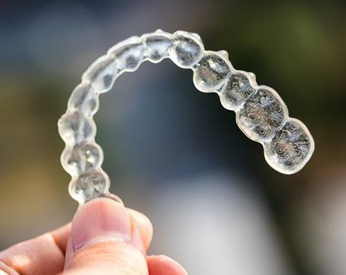 closeup of person holding Invisalign clear aligner 