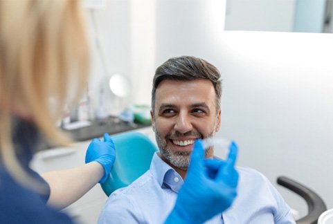Patient smiling at dentist assistant holding Invisalign aligner