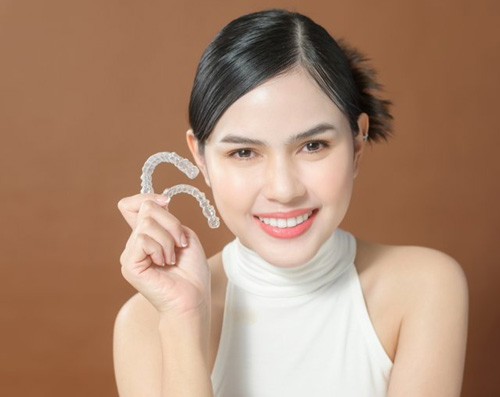 Lady smiles while showing off clear aligners