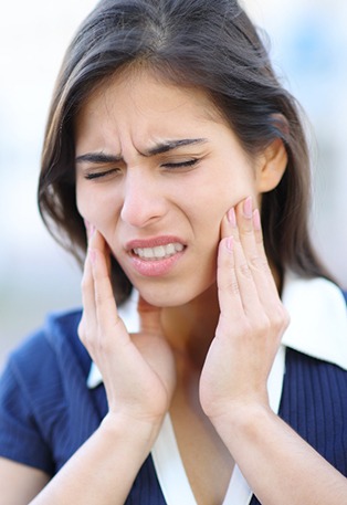 A woman holding her jaw in pain