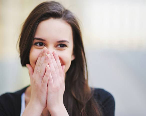 Woman covering her mouth to hide her teeth