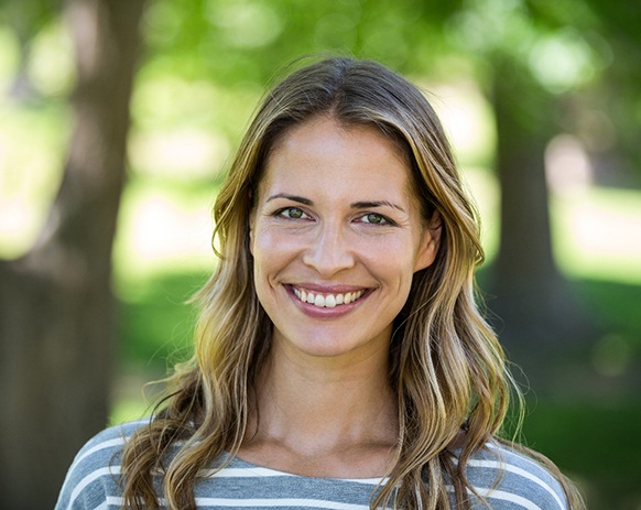 Woman in striped shirt smiling in park