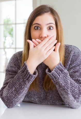Woman covering her mouth before gum disease treatment