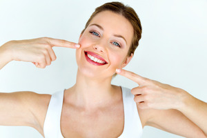 Woman pointing to bright smile after teeth whitening