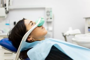 Profile view of patient in dental chair with green nitrous oxide mask over nose